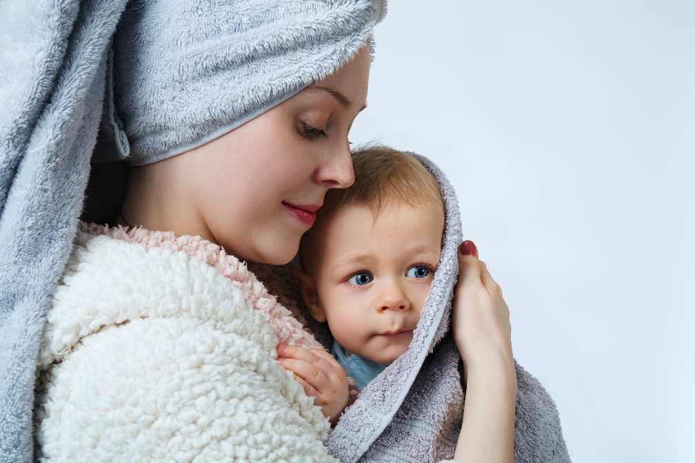 woman with baby in bathrobe and towels after washing and spa
