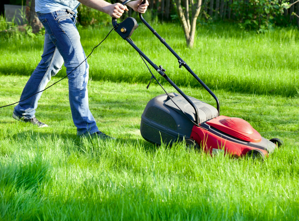 Man moves with lawnmower & mows green grass