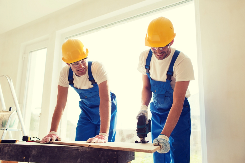 teamwork and people concept - group of smiling builders in hardhats with tools indoors