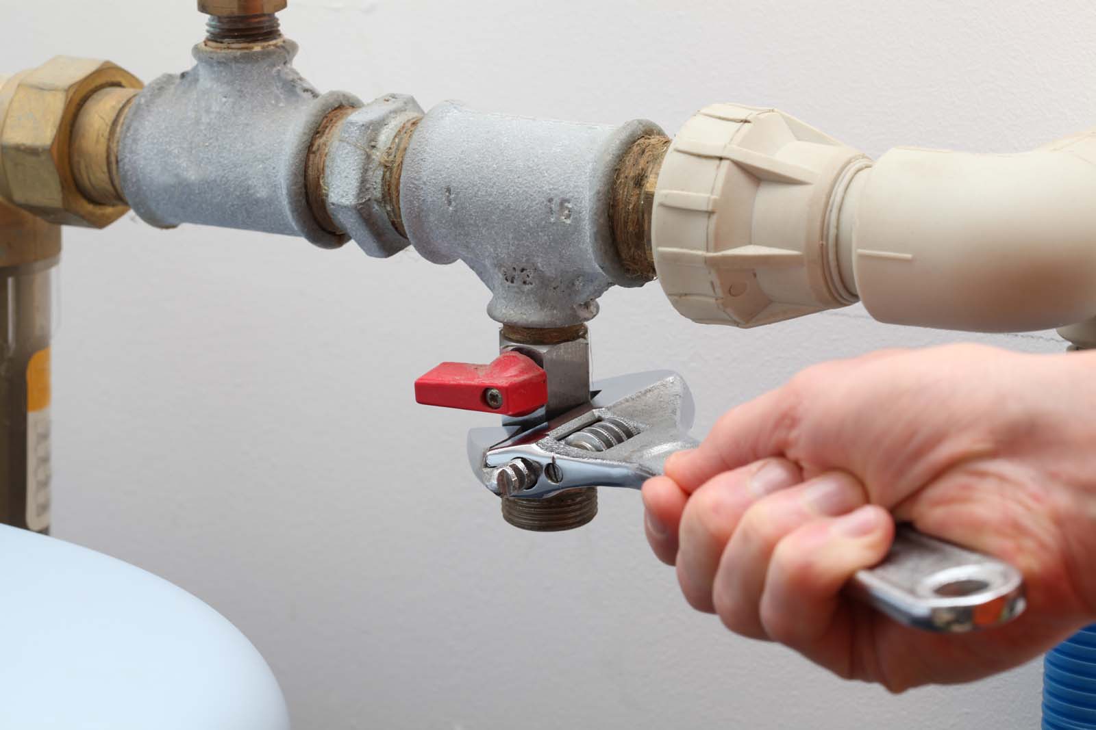 plumber working with wrench on pipe