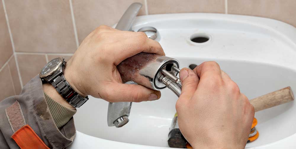 plumber working on bathroom basin tap
