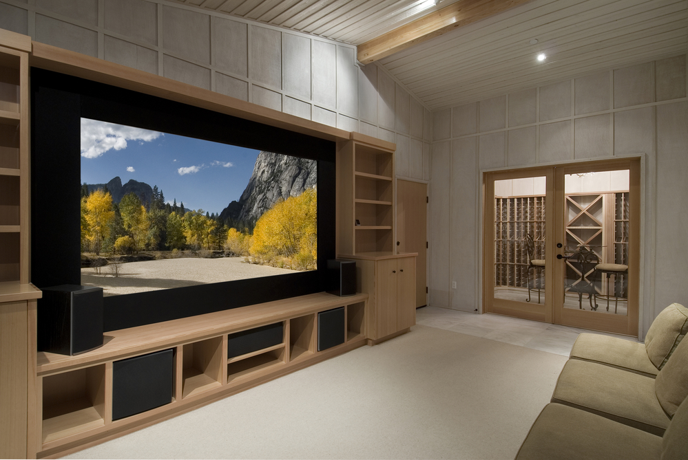 home theatre with wine tasting room, big screen, wood cabinets, photo on screen a shot from yosemite