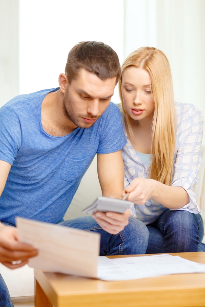 busy couple with papers and calculator at home