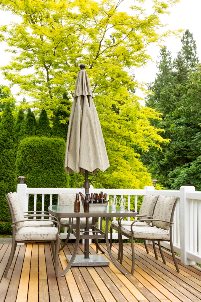 outdoor patio table with cold bottled beer in bucket and drinking glasses on cedar wood patio colourful trees in background