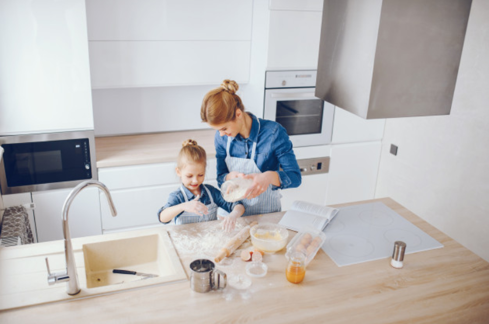 mother and daughter working on wood island counter in white kitchen