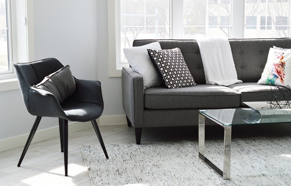grey scale image of living room with couch table and chair and colored pillow
