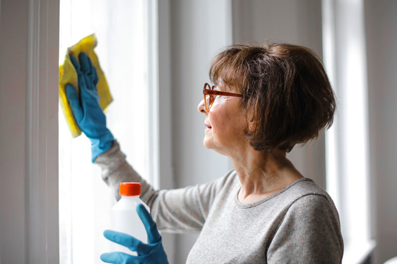woman cleaning home with disinfectant