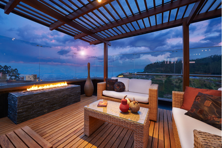patio with roof, wood flooring, fireplace, rattan furniture